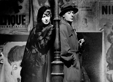 a man and a woman leaning on a street light