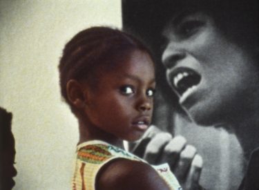 A young girl standing in front of an Angela Davis poster.
