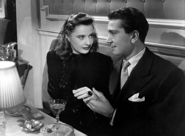 Richard Conte holding Barbara Stanwyck's hand in a restaurant booth.