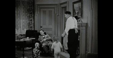 Laurel and Hardy and a toddler in a living room.