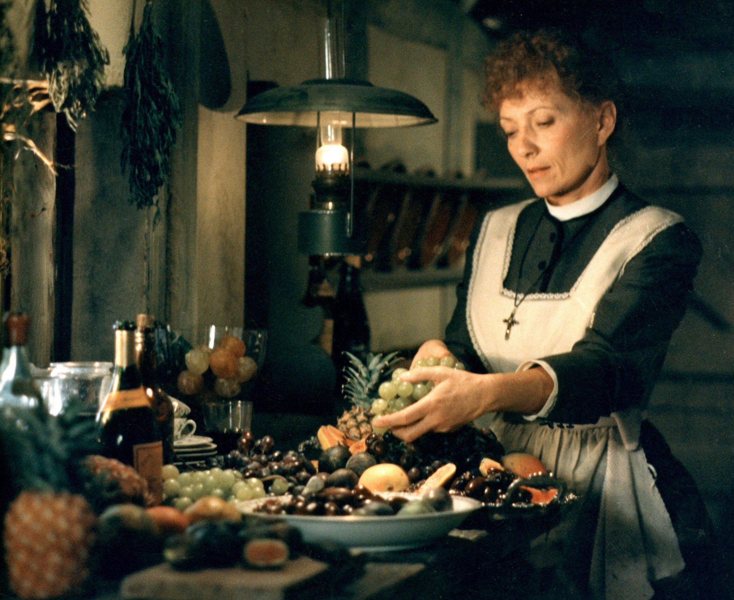 a woman in a kitchen touching a plate of fruit