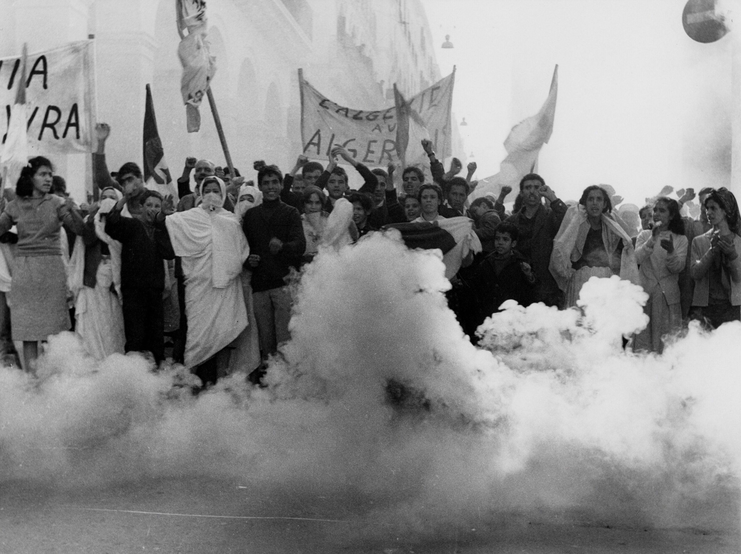 a bunch of people in protest holding signs. there is smoke around them