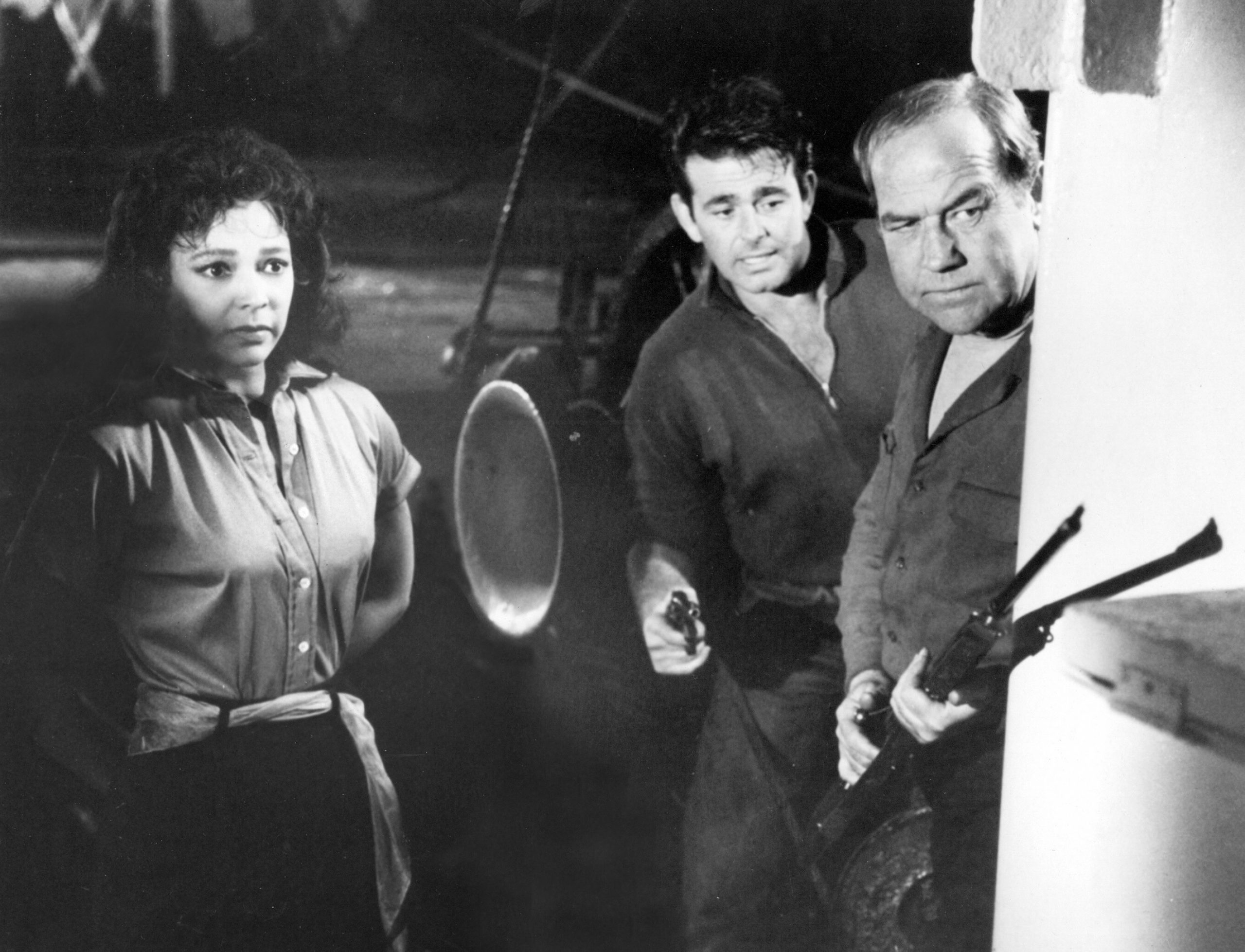 2 men and a woman looking defensive. the men are holding guns