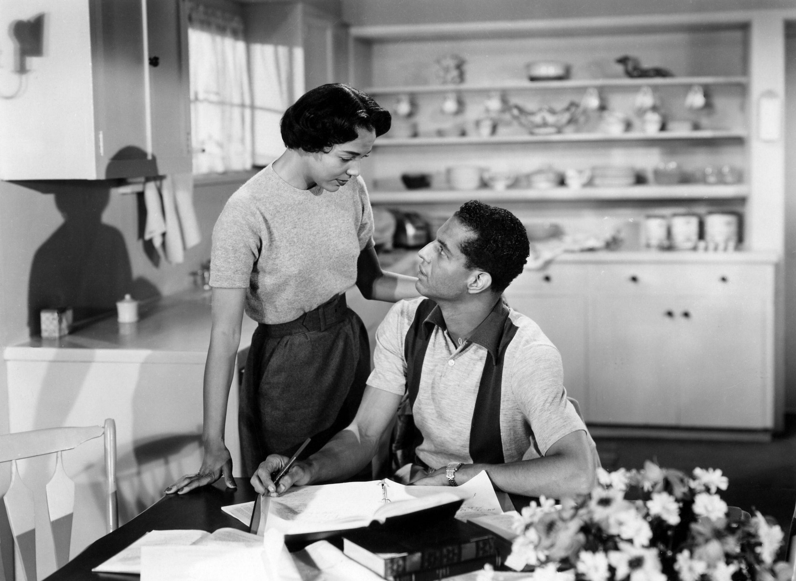 a man and a woman in the kitchen of a house looking at each other