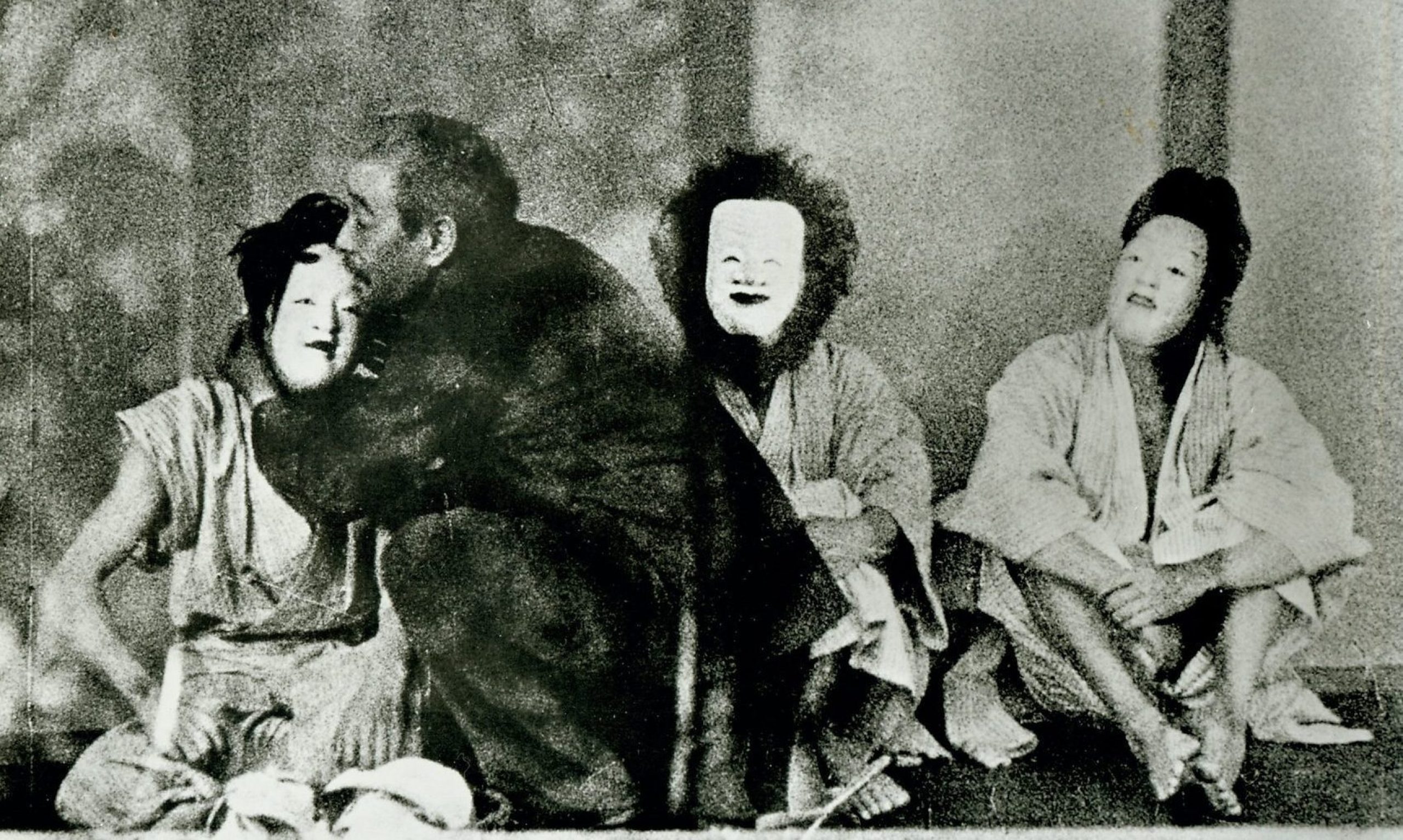 3 people with masks sitting on the floor. a man is embracing one of them
