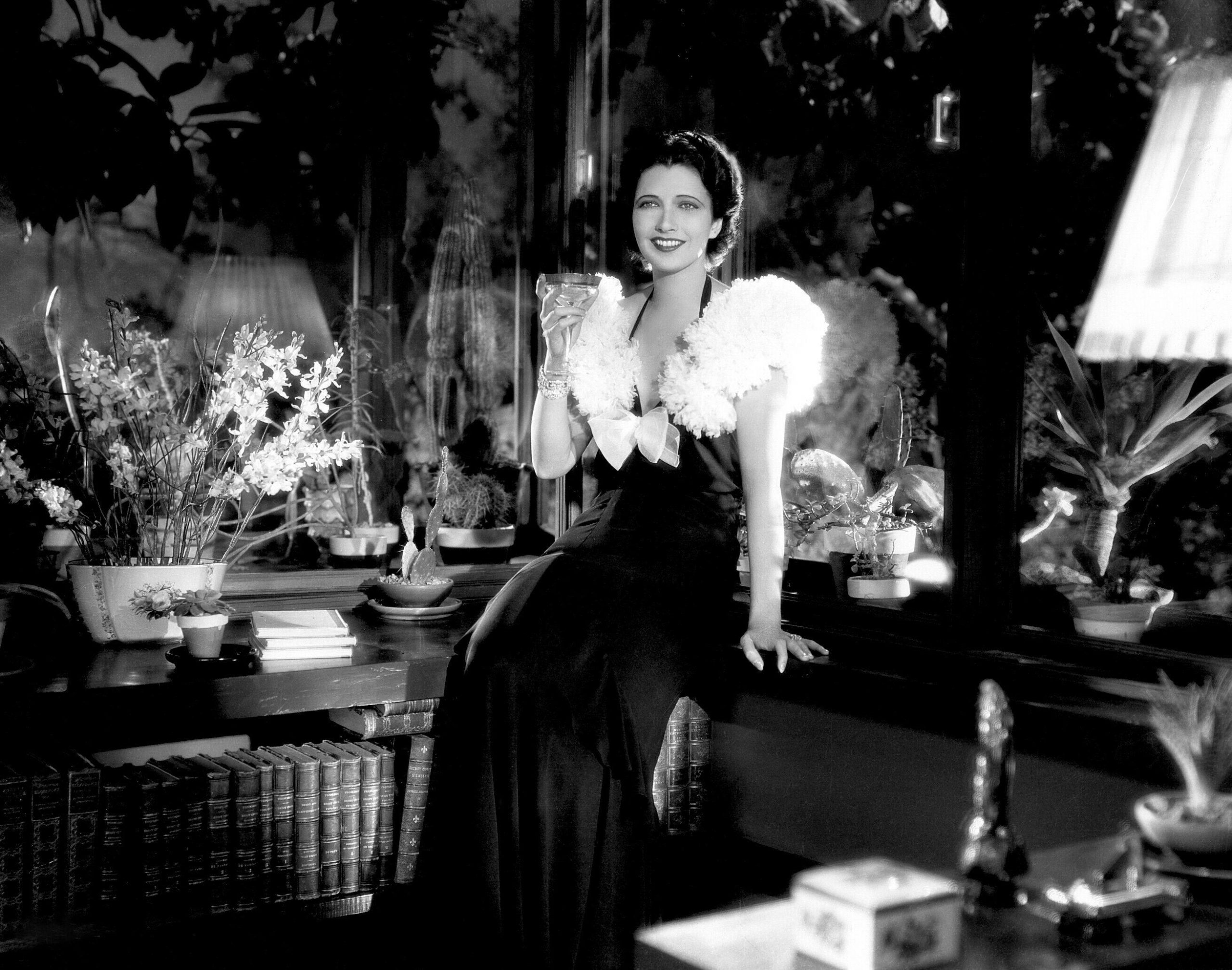 a woman in a fancy dress sitting holding a glass