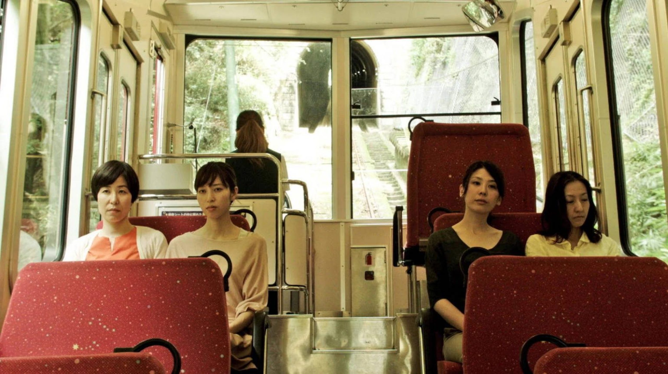 4 women sitting on a bus looking tired