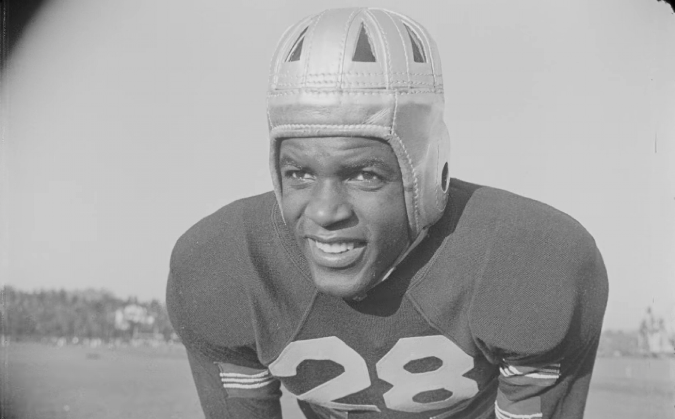 Jackie Robinson smiling in a football uniform.