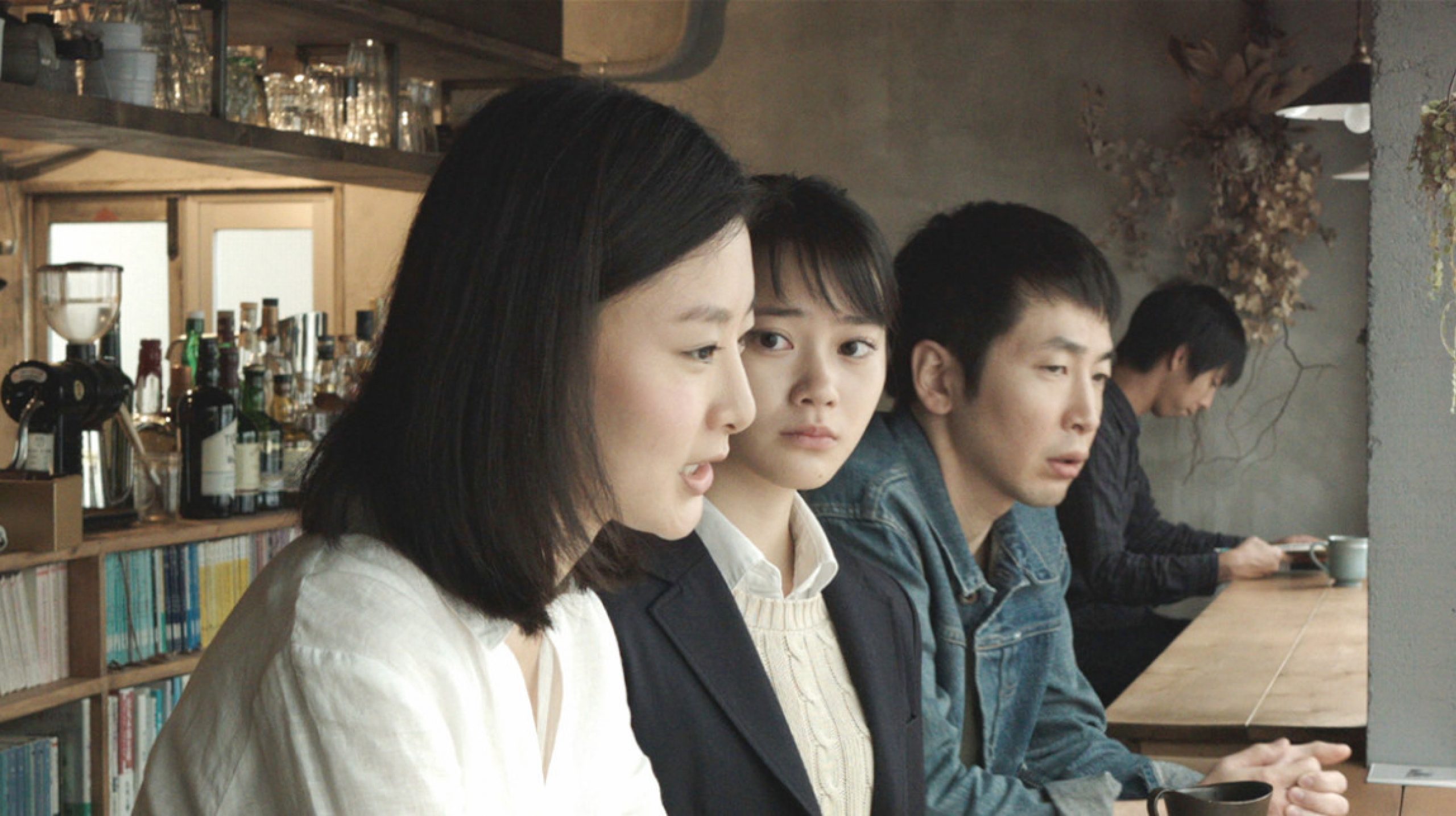 2 women and a man in a cafe looking out the window