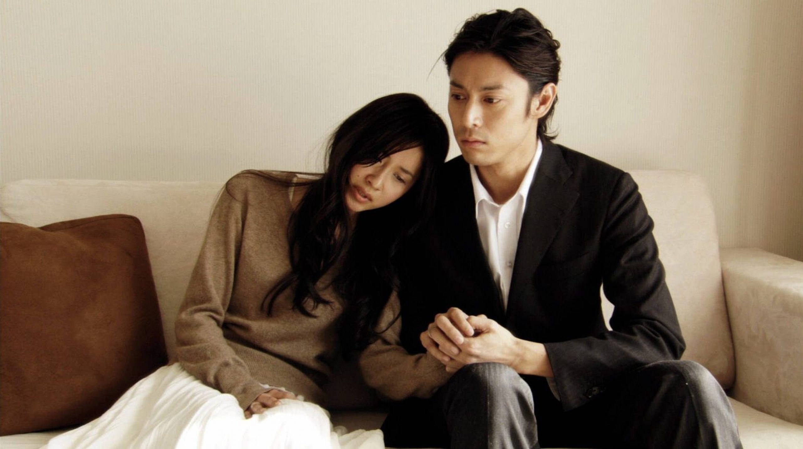A man holding a woman's hand on a sofa.
