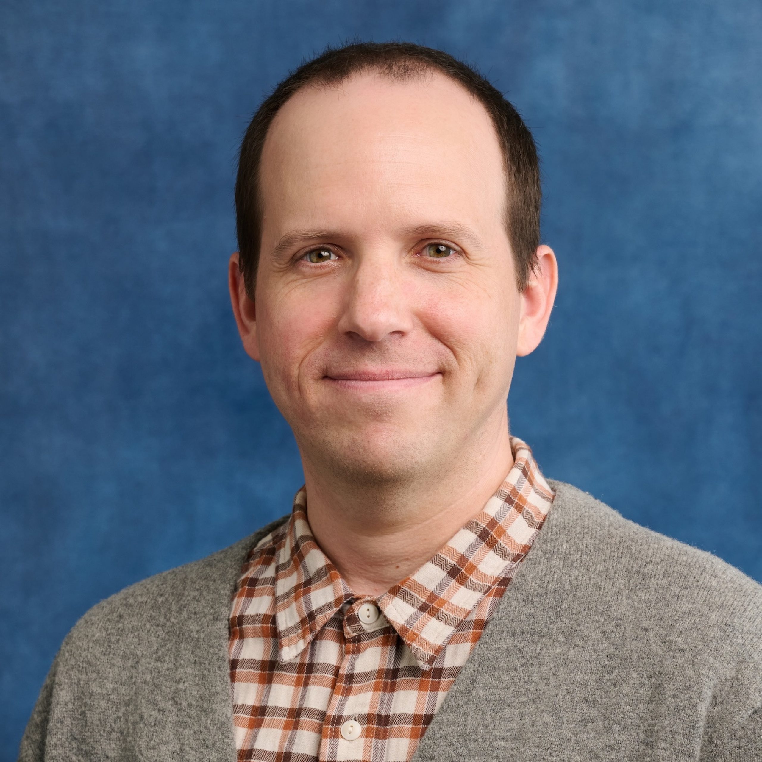Stephen Gabrielson headshot wearing plaid collared shirt and sweater