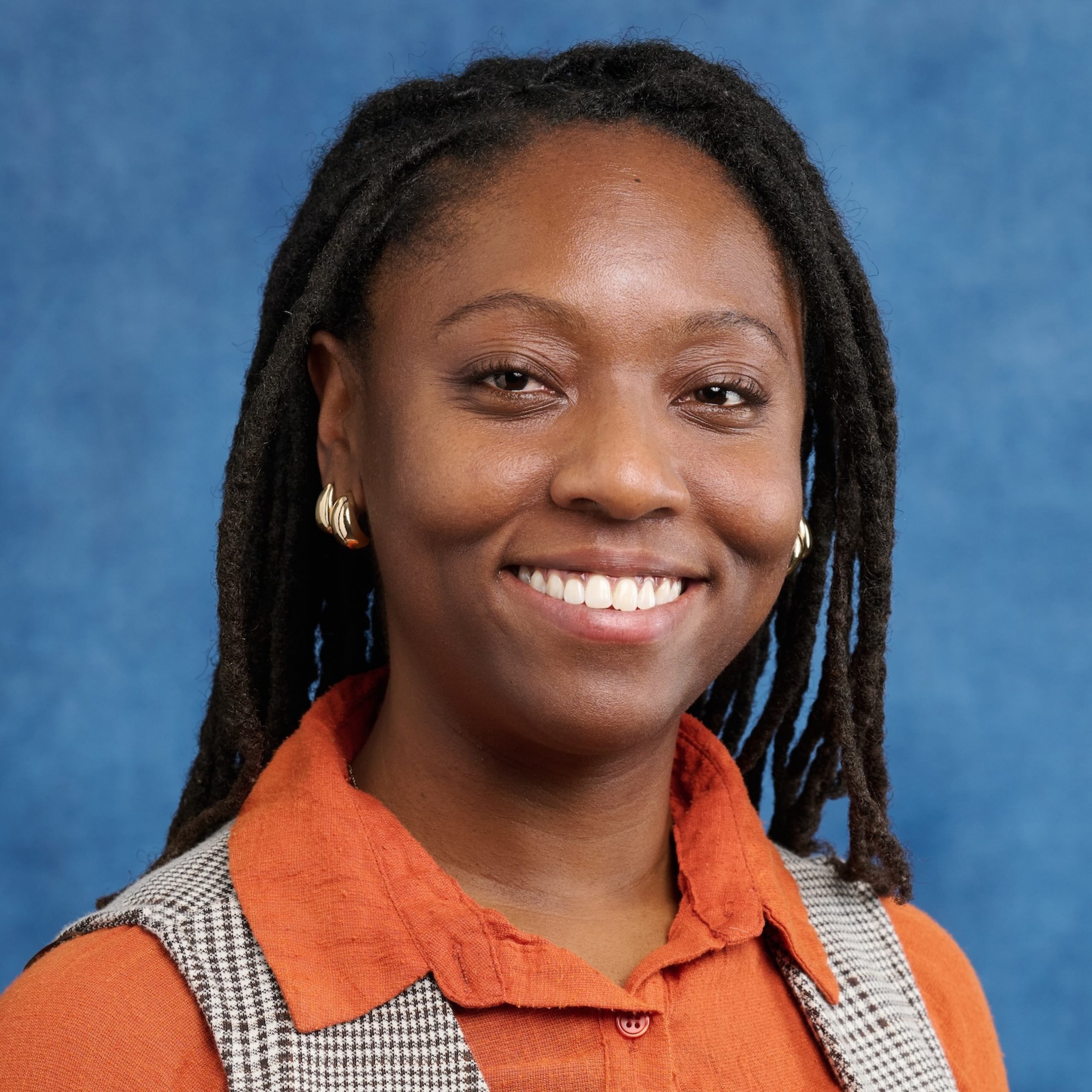 Blair Black smiling headshot while wearing orange top