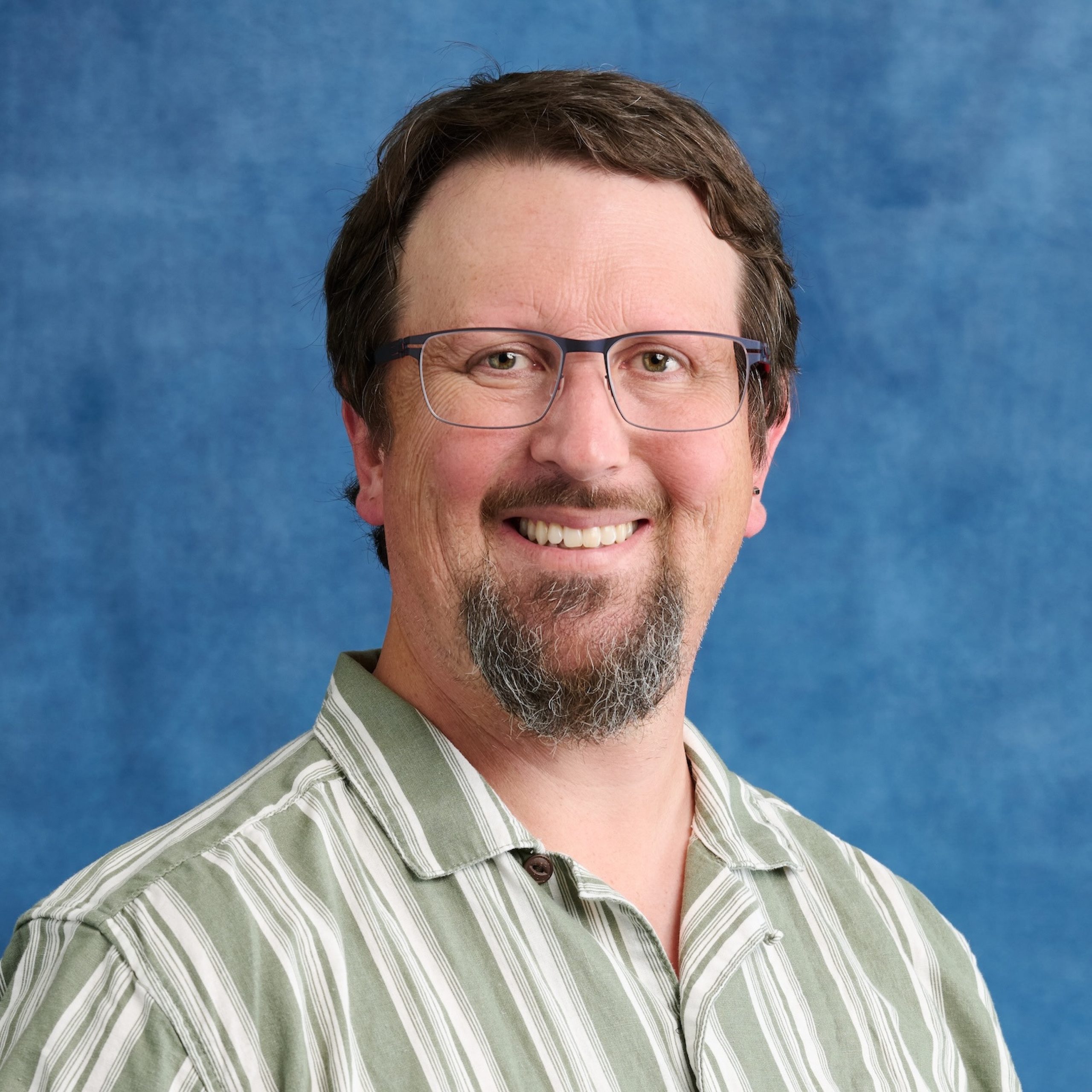 Jonathan Wilson headshot wearing striped button-down shirt