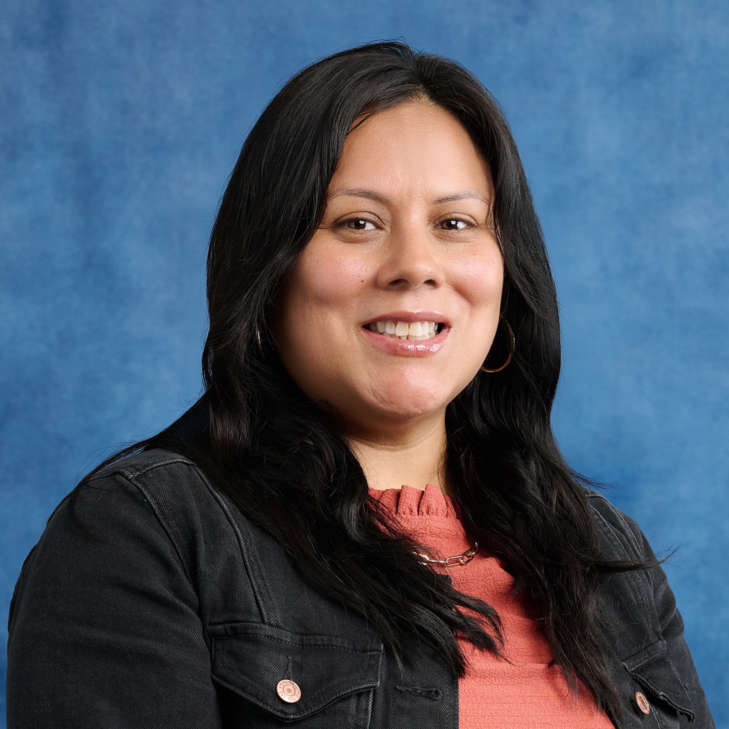 Melina Duenas Perez headshot wearing a pink top and dark jacket