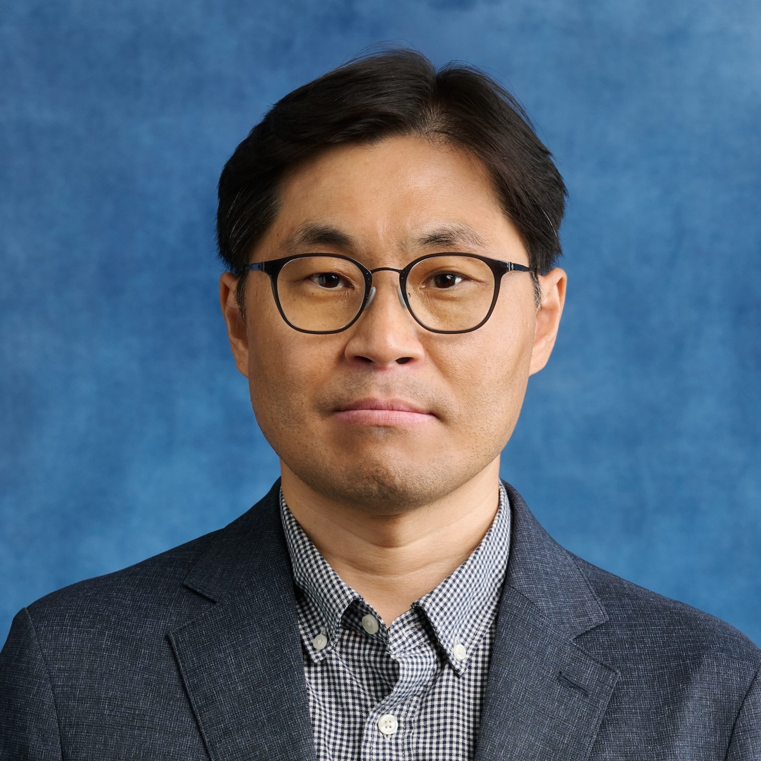 Sanghun Cho headshot wearing glasses and collared shirt and jacket