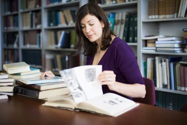 Woman reading books while sitting at a table