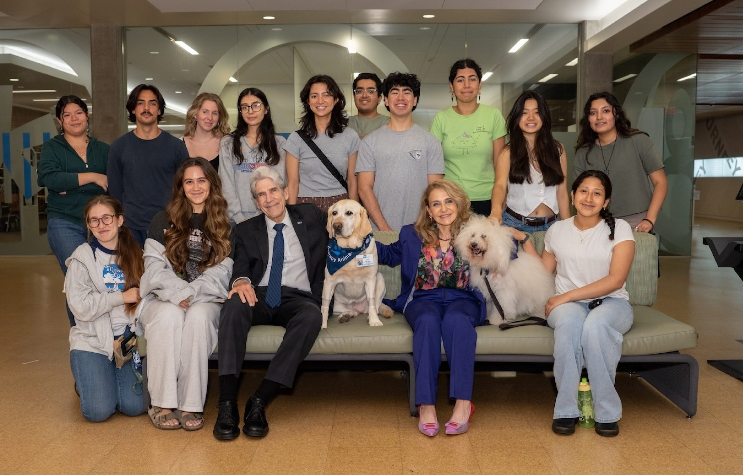 Chancellor Frenk and a group of students in YRL library with therapy dogs