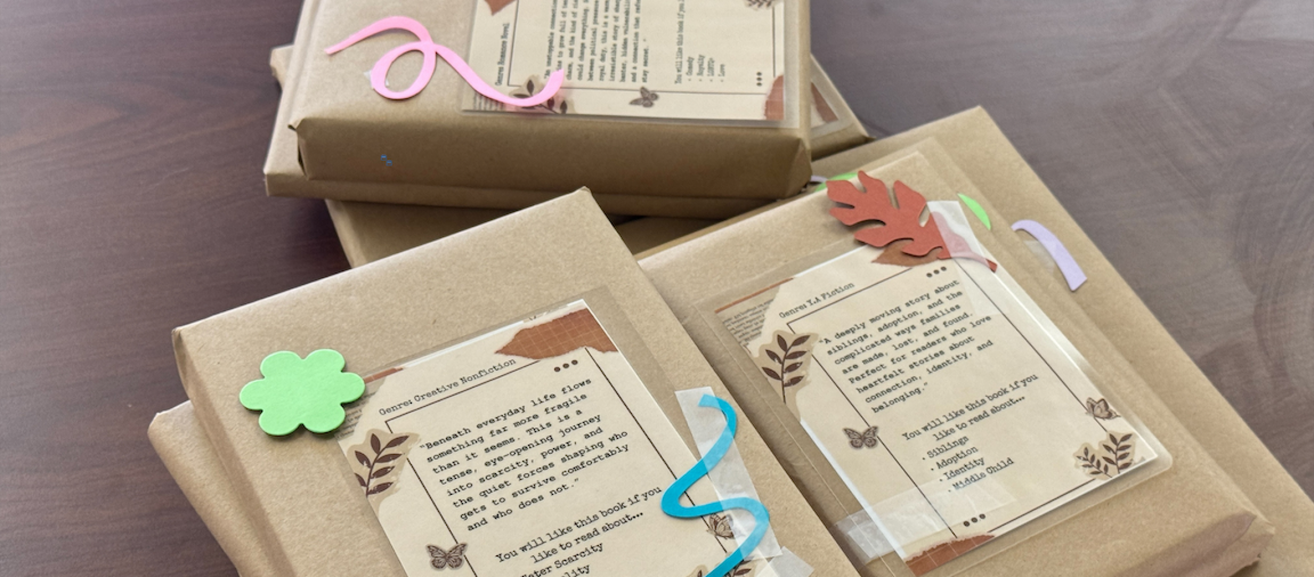 Background of pages from different books with a book wrapped in paper and tied with a ribbon laying on top next to a small wrapped box with a bow