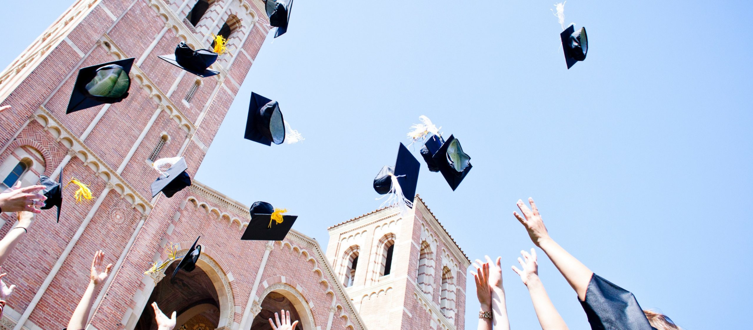 people throwing graduation caps in air