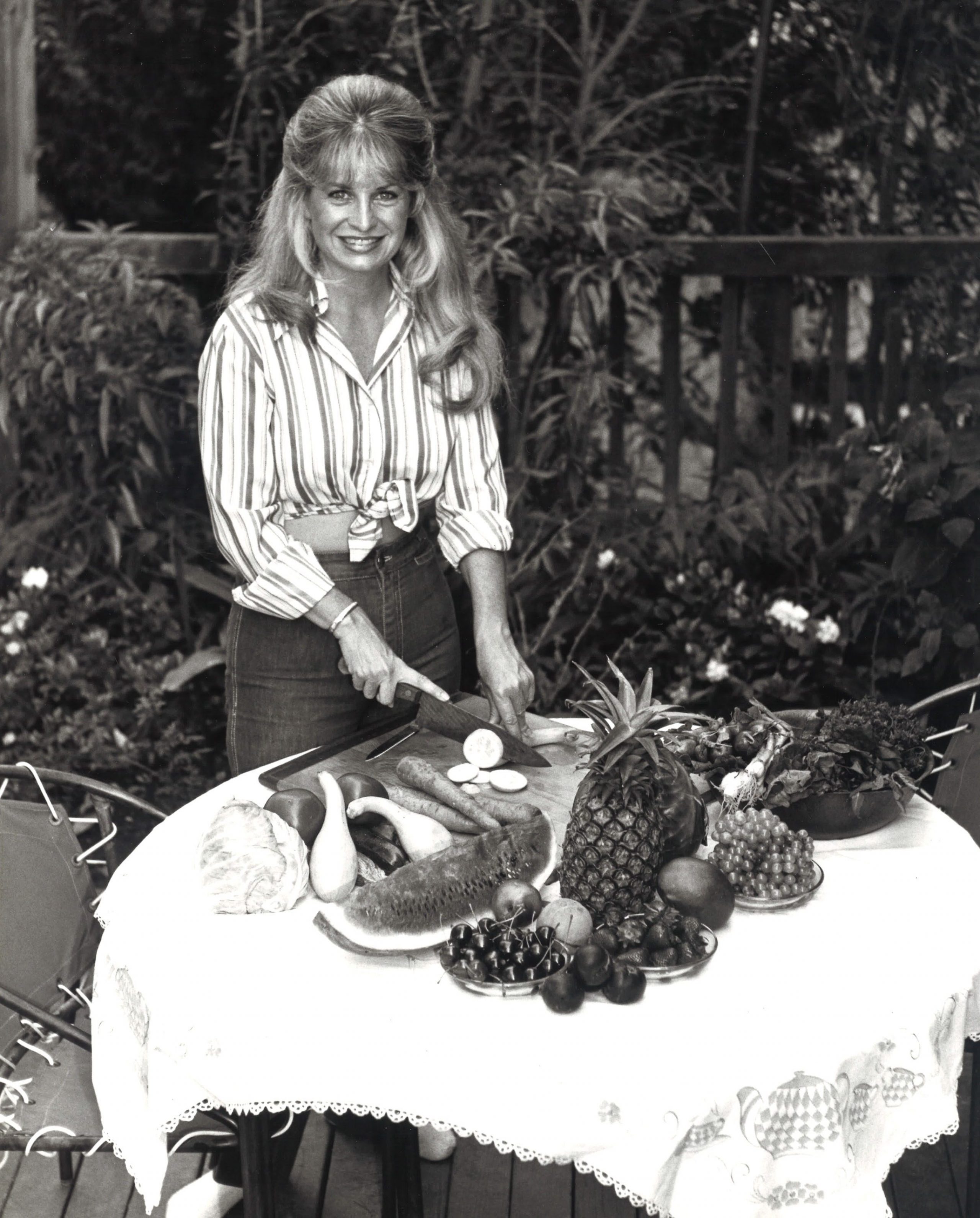 black and white image of Mrs. Gooch, a woman with blond hair at a table full of food
