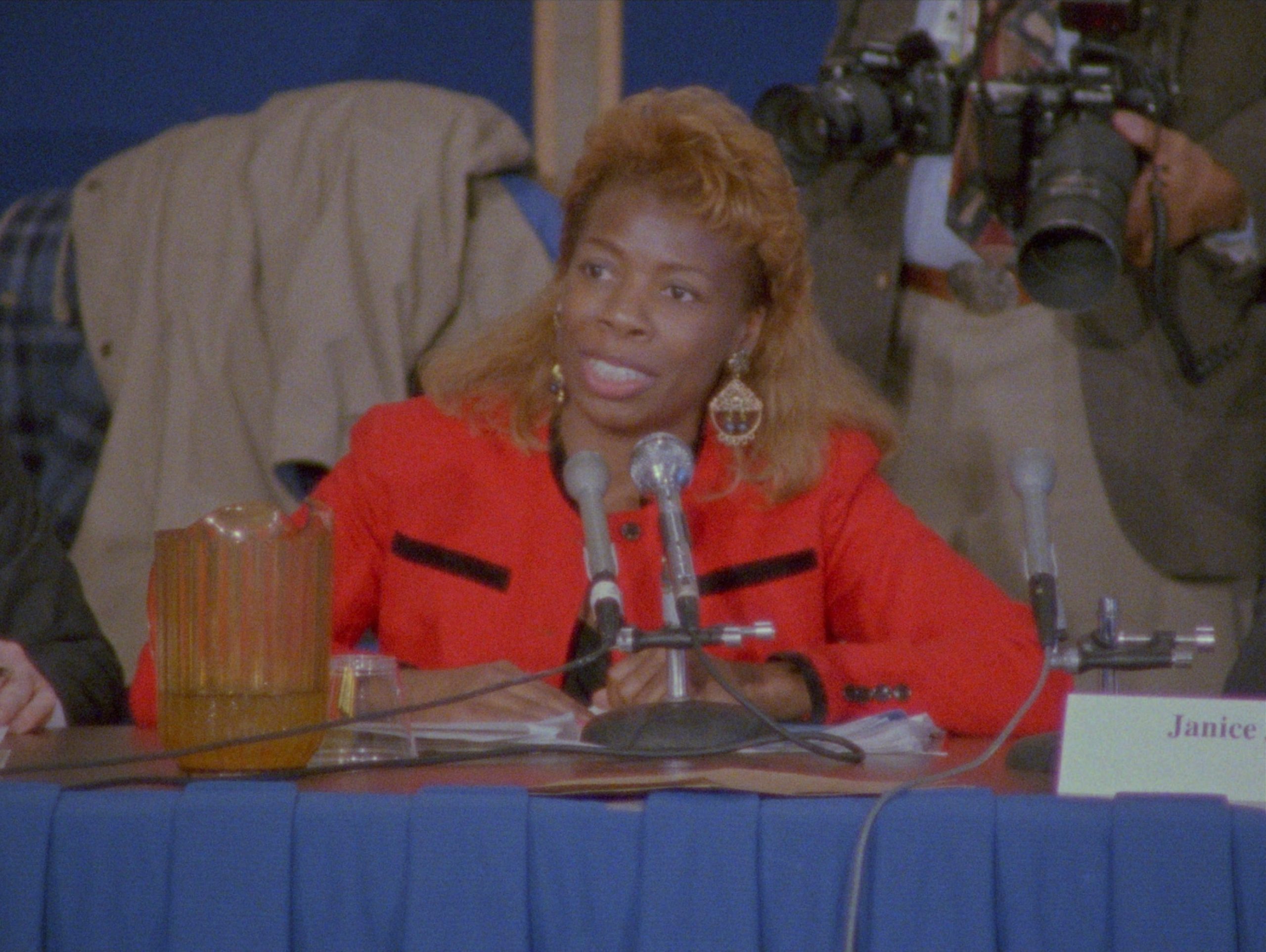 woman in red seated in front of a microphone