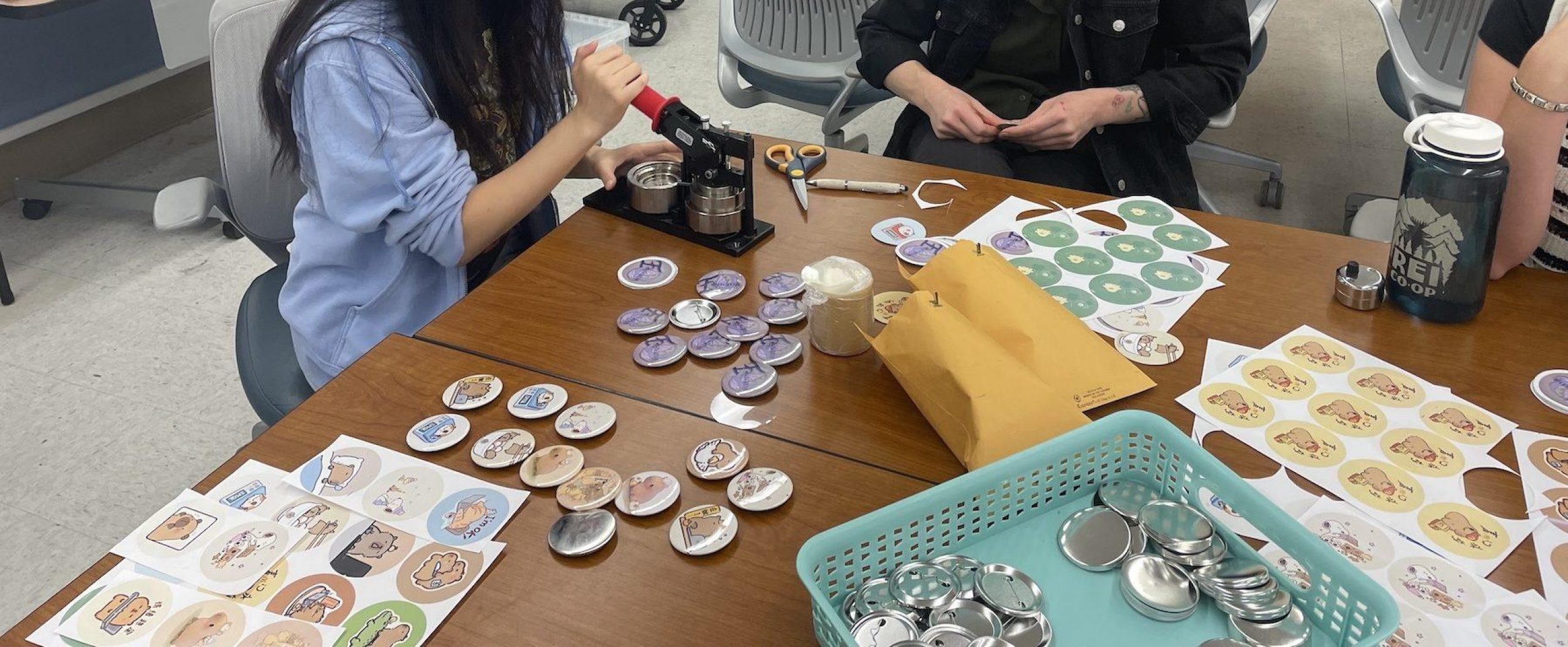 two people making buttons at a table