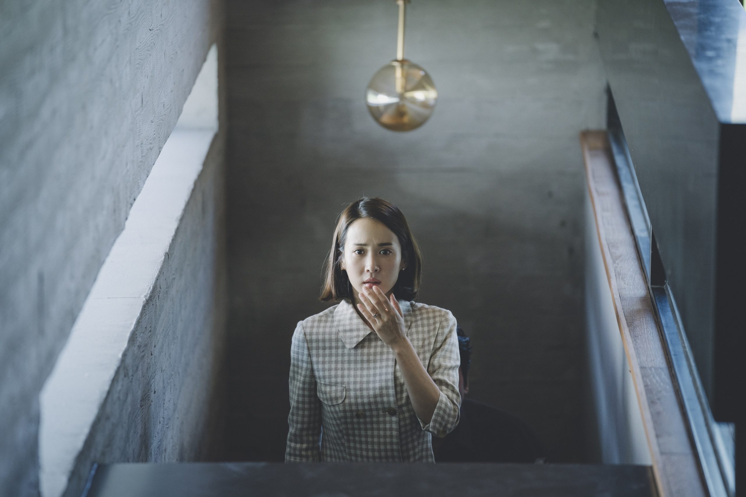 woman standing on stairs looking upward with surprised and worried look on her face