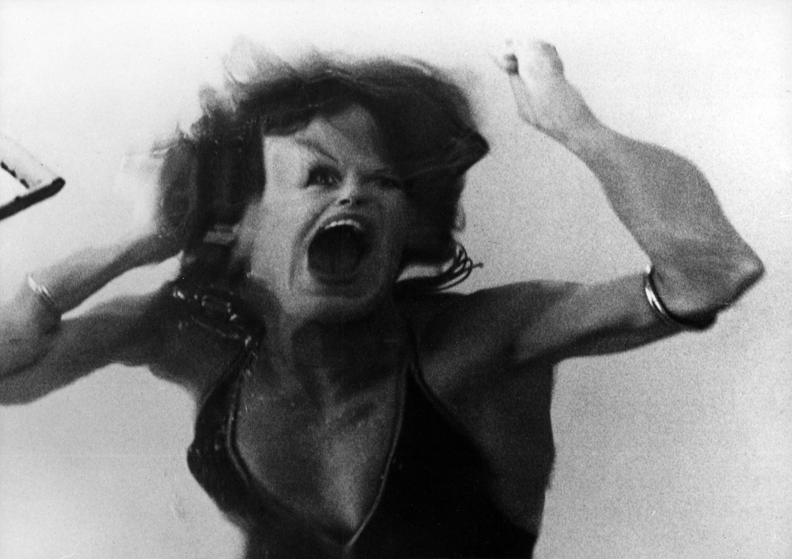 Still from "Legacy". A woman's face in distortion mid-scream.