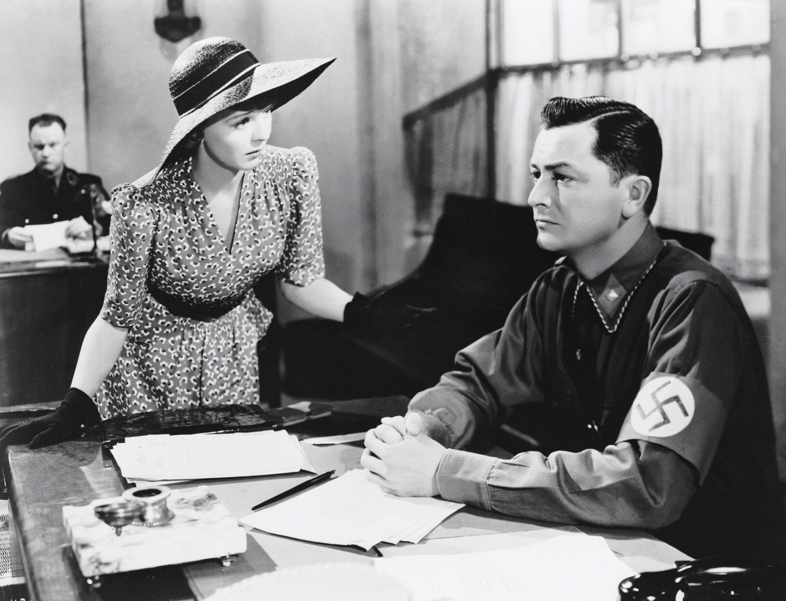 woman talking to man in uniform with swastika who is ignoring her