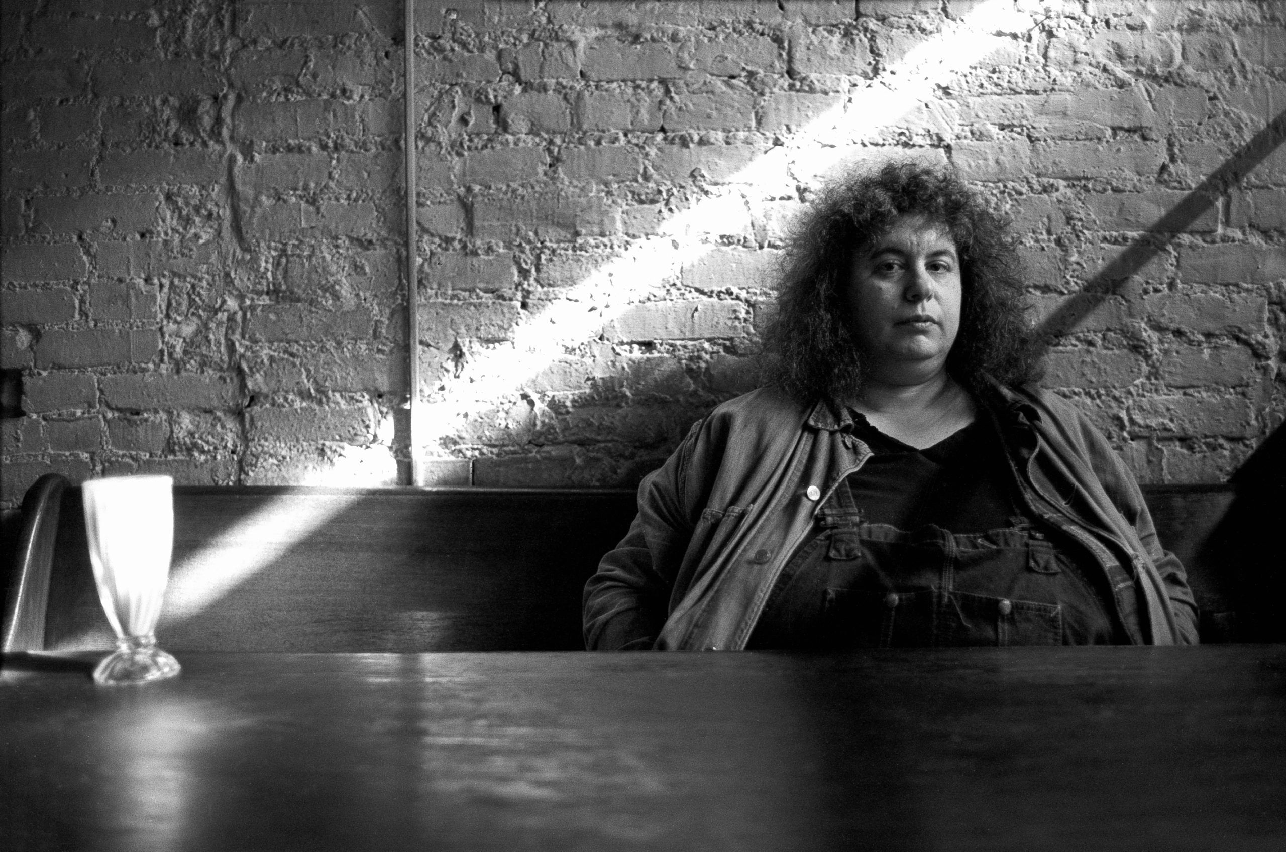 A black and white image of a woman sitting exacerbated on an indoor bench