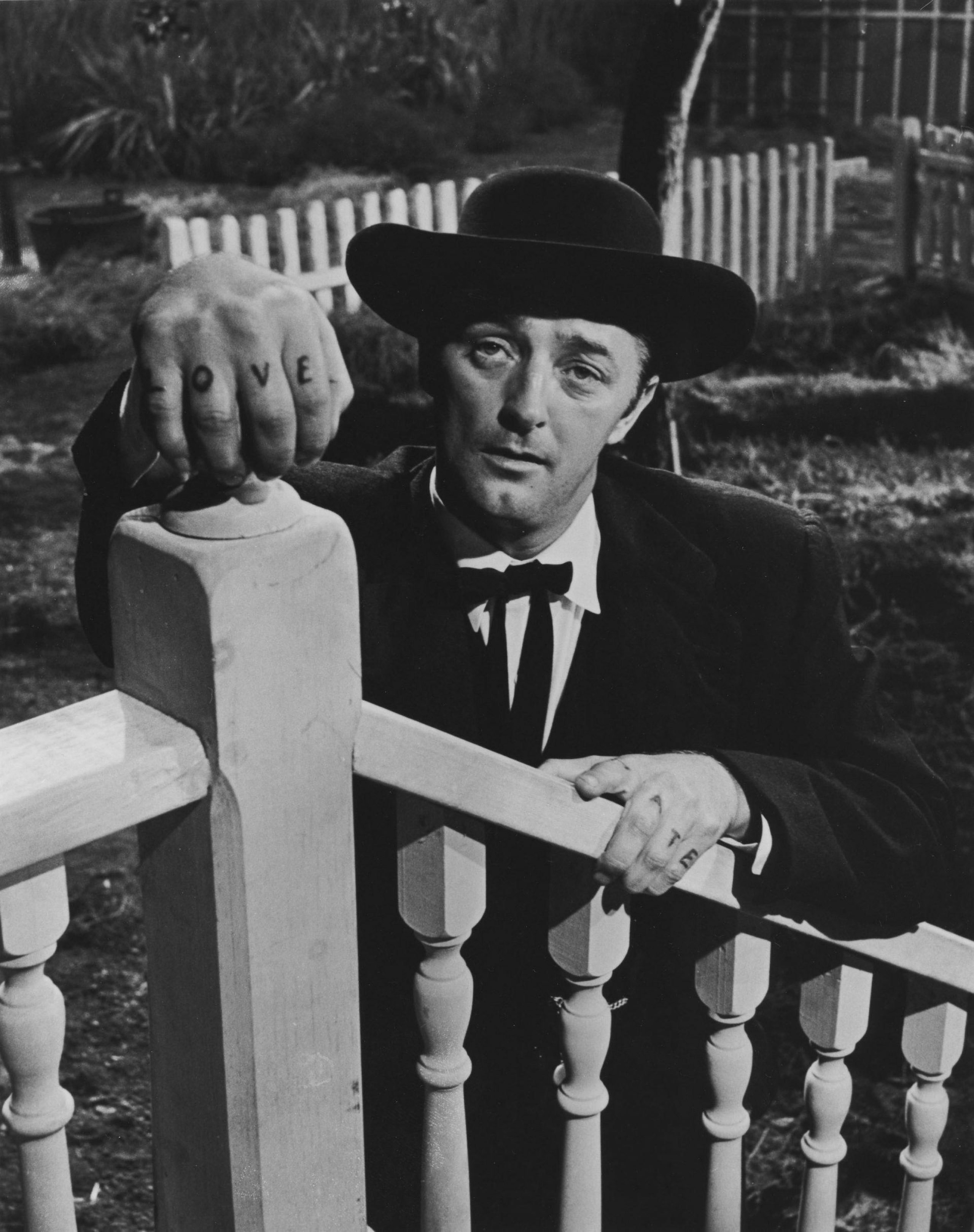 Still from "The Night of the Hunter". Man in suit and fedora hat with "LOVE" written across his knuckles