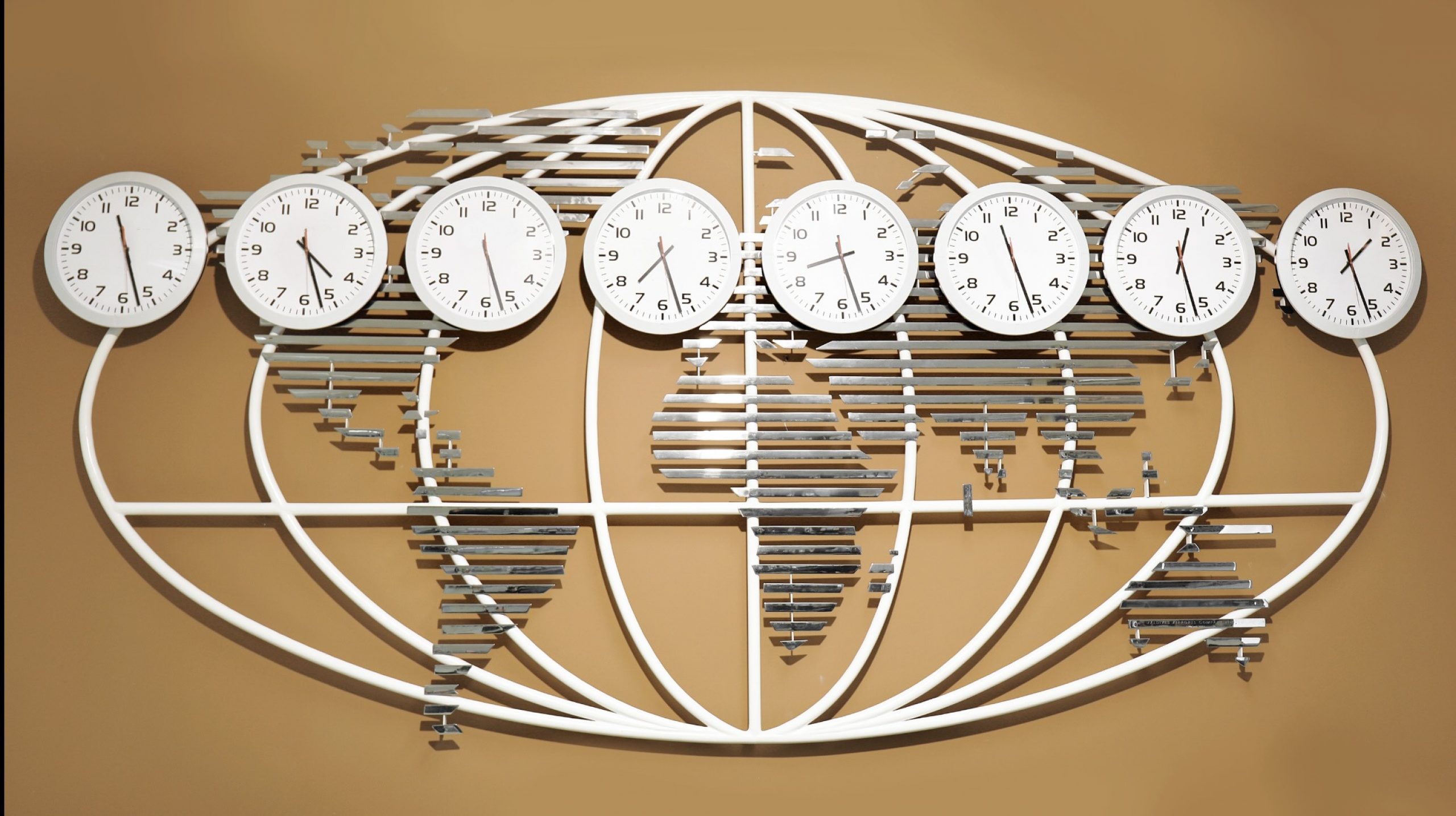 world globe map on a wall with multiple clocks showing different time zones