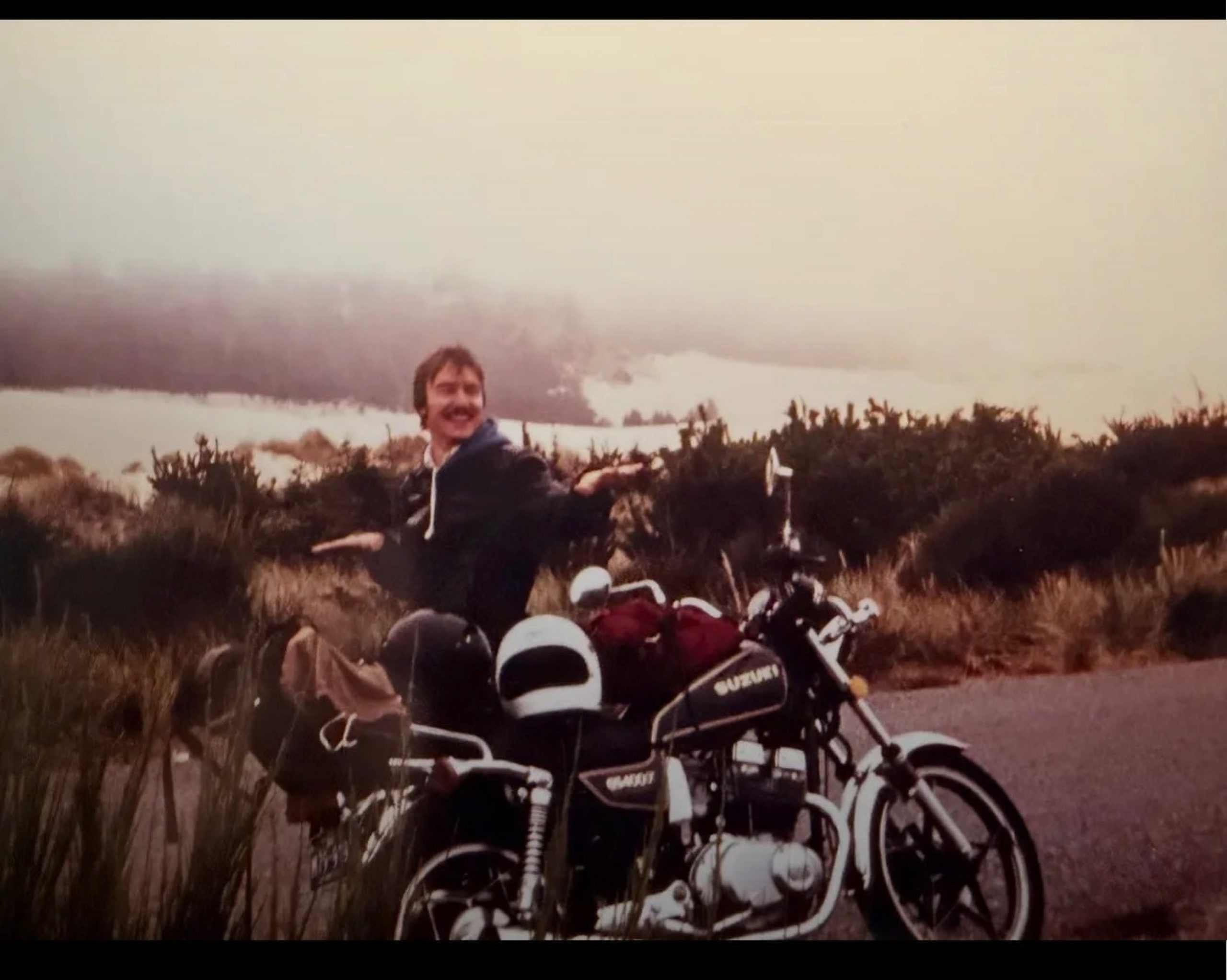 Younger Robert Gore on a motorcycle with orange red sky behind him