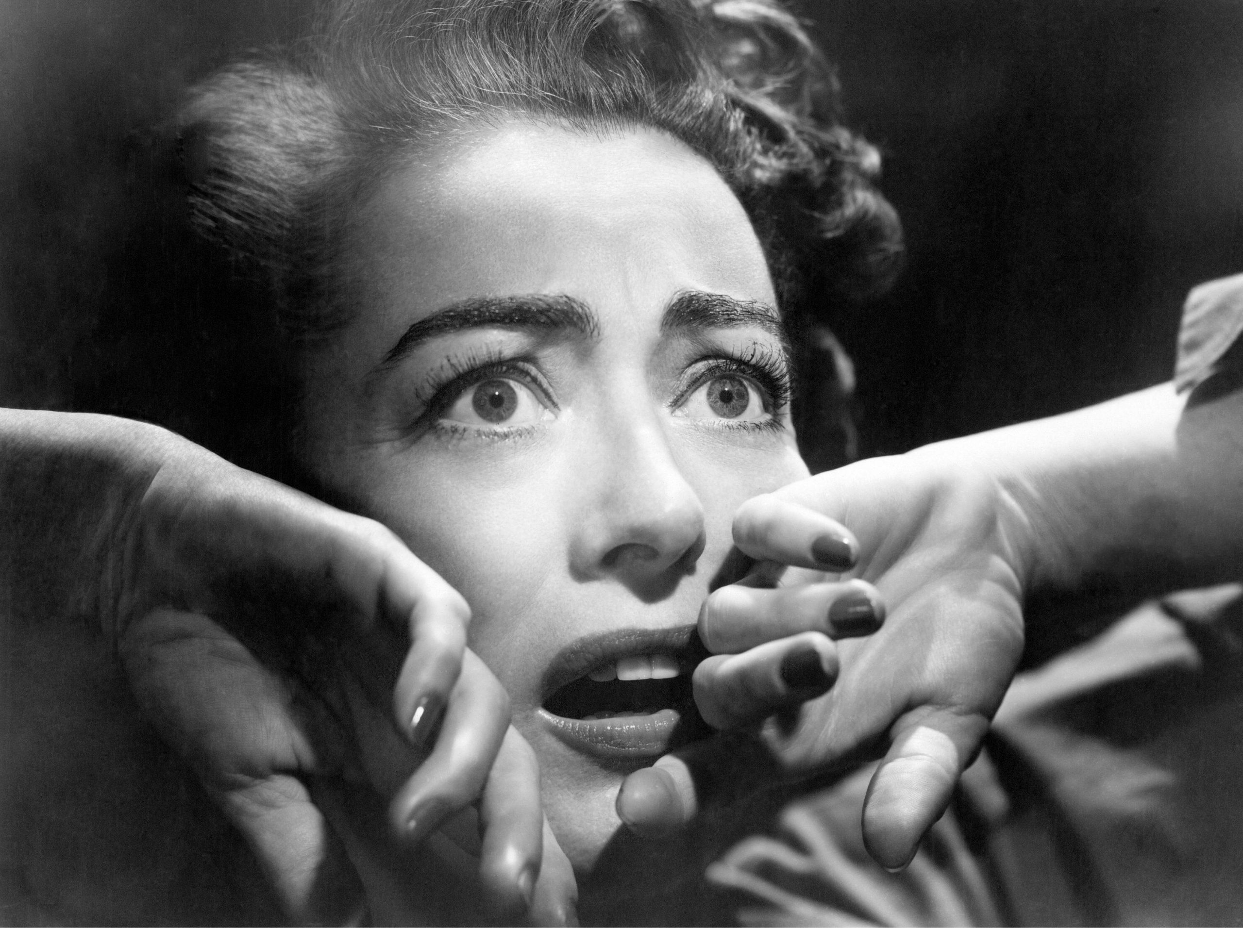 A black and white image of a frightened woman's face