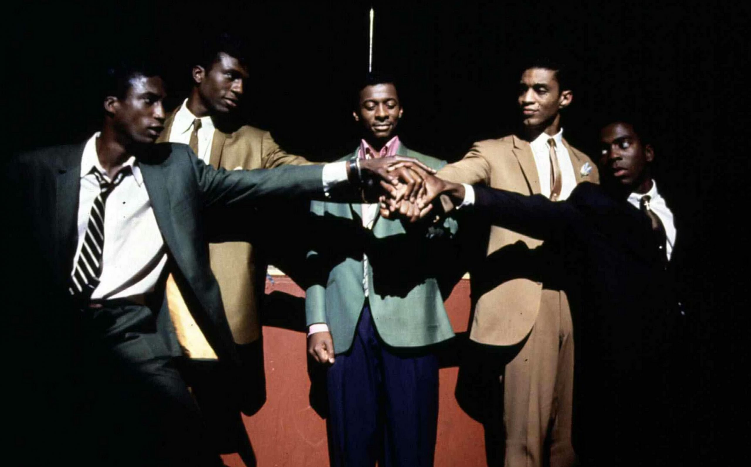 Still from "The Five Heartbeats". African American musician group facing each other and stacking hands on top of one another.