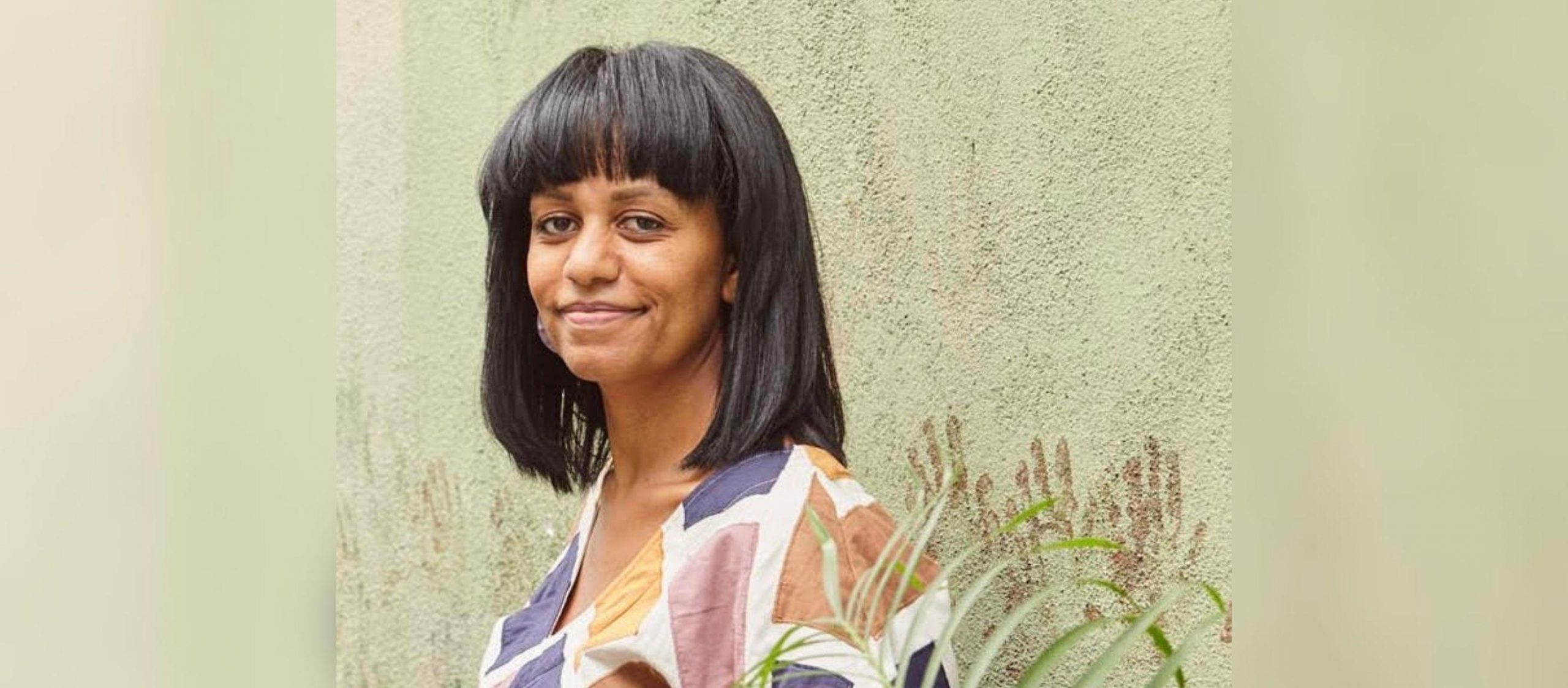 Nesanet Teshager Abegaze stands in front of green wall