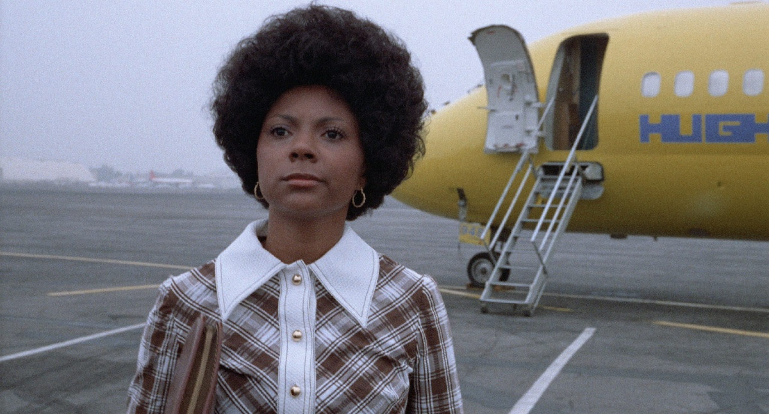 still from the 1972 film 1972 "Black Girl," woman standing in front of plane on the tarmac