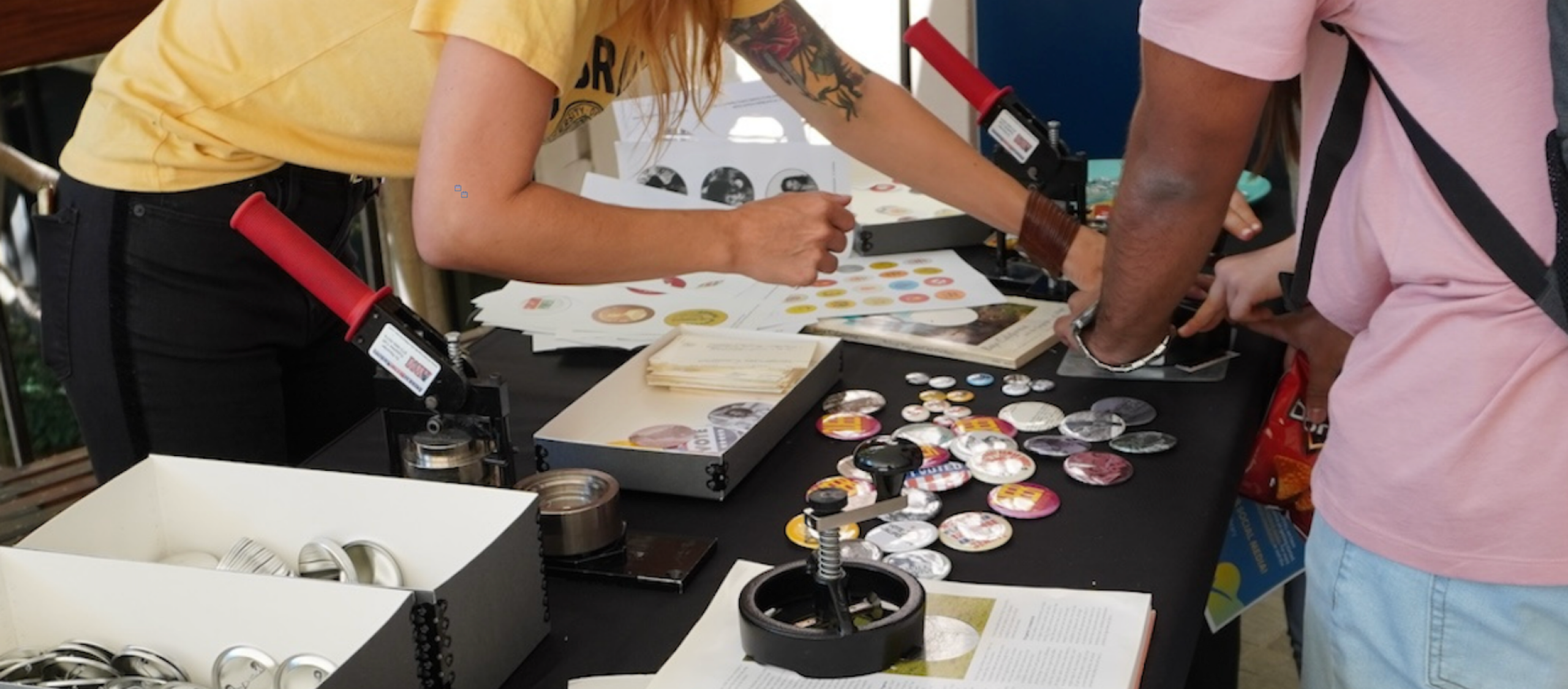 people using a button maker and buttons on a table