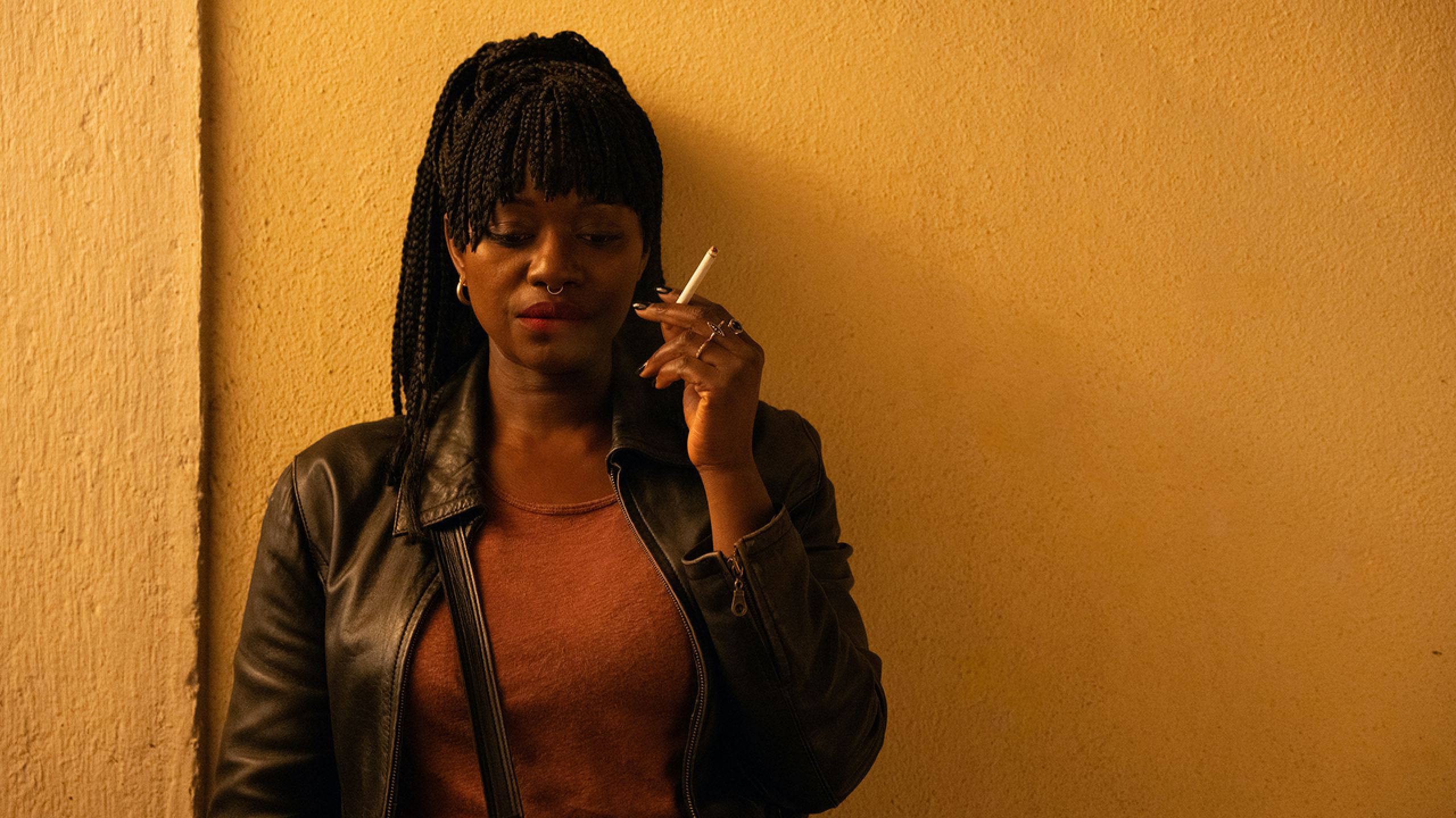Woman with dark hair wearing jacket and holding a cigarette